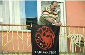 Memes HOTD: imagem de senhor pendurando a bandeira da Casa Targaryen na janela. Imagem: Reprodução.